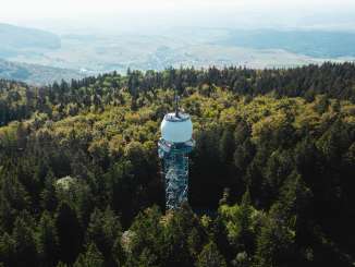 Hagenturm Merishausen A tall metal observation tower rises out of a forest. Above the viewing platform is a large white sphere.