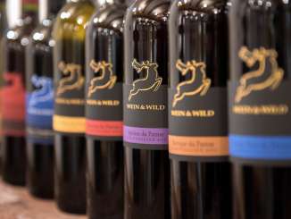 Es stehen diverse Weinflaschen in einer Reihe mit einem Etikett mit einem Hirsch und dem Titel "Wein & Wild".