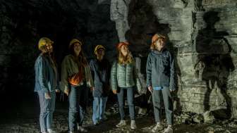 Five female friends are wearing yellow and orange helmets. They are standing in a former gypsum mine.