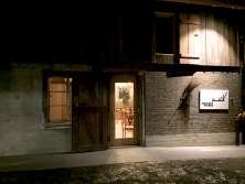 The facade of an old barn. Seating can be seen through the door. On the right-hand side of the entrance is a sign sayingHirschen Bühne".