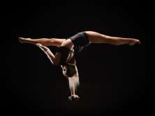 An acrobat balancing herself on one arm.