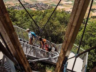 Four people walk up the stairs of the Siblingen edge tower. A tower on wooden and metal stairs.