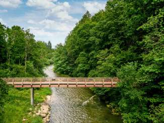 Wutach Schleitheim bridge A wooden bridge over a river. To the left and right is a forest.