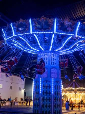 In a large hall there is a chain carousel that shines with blue light.