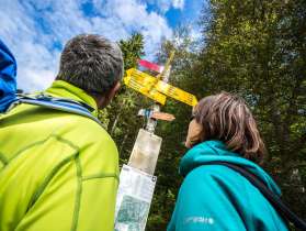 Two hikers look at a hiking signpost.