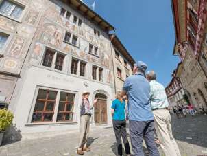A group stands in front of a house with painted facades. A guide tells us more about it.