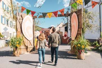 A couple holding hands. They walk through the colorfully decorated alleyways at the autumn festival in Wilchingen.