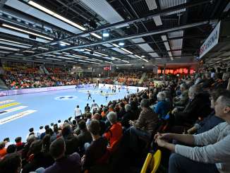 A handball pitch with filled spectator stands. The pitch is blue. The words "BBC Arena" can be read on a banner.