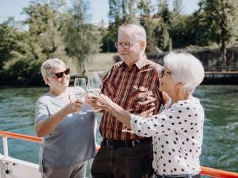 Three elderly people are tasting wine on the regular boat service on the Rhine between Schaffhausen and Stein am Rhein.