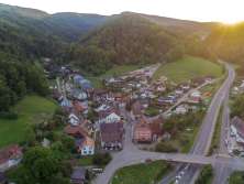 A bird's eye view of a small village surrounded by wooded hills.