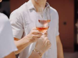 Two people toast with a glass of rosé.