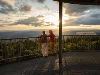 A mother stands with her daughter on the viewing platform of the Hanturm tower. The sun is about to set.