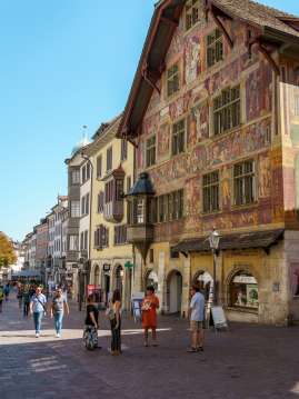 Guided tour of Schaffhausen A group with a guide stands in front of a house richly decorated with facade paintings and an oriel windows.