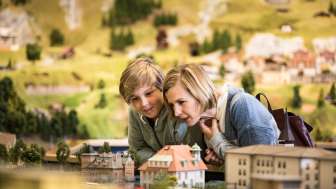 A mother and her son are in the miniature world of Smilestones. They are looking at houses.