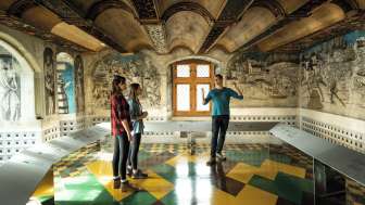 A group of three people stand in a room in the St. Georgen Monastery Museum.
