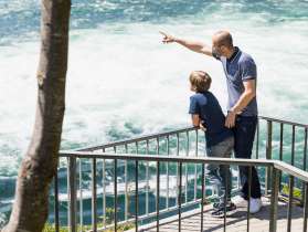 Family at the Rhine Falls A father stands with his son at a viewpoint and looks at the Rhine Falls.