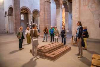 A group with a guide stands around gravestones in a church.