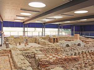 The remains of a former Roman thermal bath can be viewed in a large hall as a museum.