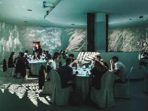 A la Art One room is set up for a banquet. The room has screens on the ceiling, floor and walls.