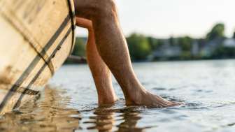 A person is sitting in a wicker boat, dangling their feet in the Rhine.