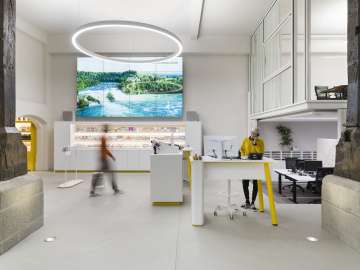 Visitor Centre Schaffhausen This is the counter area of the Schaffhausen Visitor Center. A woman in a mustard yellow sweater is standing at a high table talking on the phone. Another person walks to the free counter.