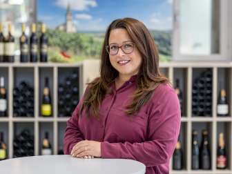 Portrait Tanja Hürlimann. She is wearing a burgundy colored blouse. She has long brown hair and wears a birlle.