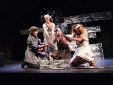 Disguised theater actors playing with water on a stage and splashing themselves wet.