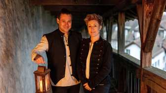 A woman and a man on a fortress. The man holds a lantern.