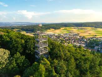 Beringer Randenturm An angular metal tower rises out of the forest on a hill. Below you can see the village of Beringen.