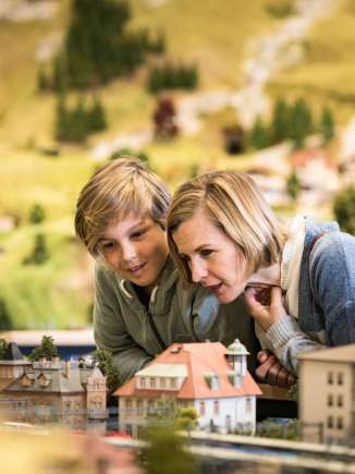 Miniature world of Smilestones A mother and her son are in the miniature world of Smilestones. They are looking at houses.