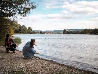 Two girlfriends are slipping stones on the banks of the Rhine outside Stein am Rhein.