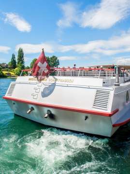 View of the rear of a white passenger ship flying a Swiss flag.