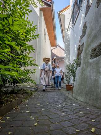 A group with a guide in traditional costume walks through a very narrow alley.