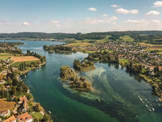 A view from above of the green-turquoise Untersee with the island of Werd. Along the shore are small _villages and green countryside.