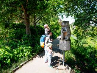A family stands in front of a carved wooden beaver. This is the start of the beaver trail in Thayngen.