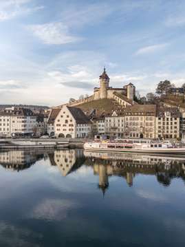 View from the clear Rhine to the wintry Old Town with ship and Munot.