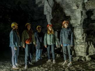 Five female friends are wearing yellow and orange helmets. They are standing in a former gypsum mine.