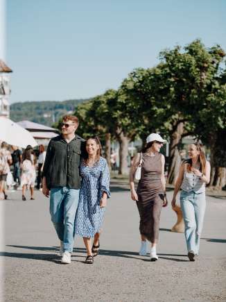 Four people stroll along the riverside promenade in Stein am Rhein in summer.