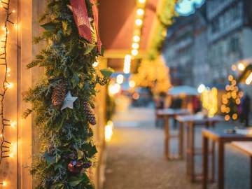 Ein Holzstand ist weihnachtlich geschmückt. Im Hintergrund erkennt man verschwommen die Steiner Altstadt.