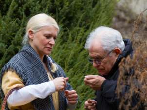 A guide dressed in a bright yellow robe gives a man something to smell.