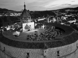 View from above of a round fortress. There is a large screen on the pinnacle and moviegoers sit in front of it.