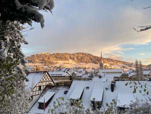 View of the old town of Stein and Hohenklingen Castle. The roofs of the houses are covered in snow and the evening sun casts a golden light.