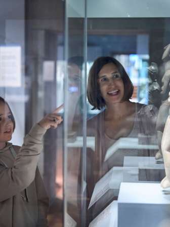 A mother and her child are in a museum looking at sculptures.