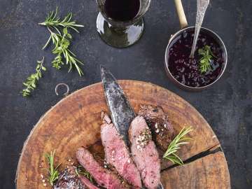 Several pieces of venison are arranged on a wooden platter.