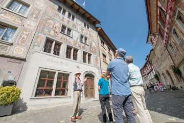 A group stands in front of a house with painted facades. A guide tells us more about it.