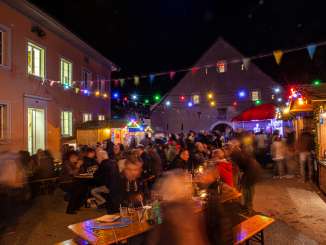 Benches lining a street in Löhningen, various stalls, and colorful string lights, with lots of people around.