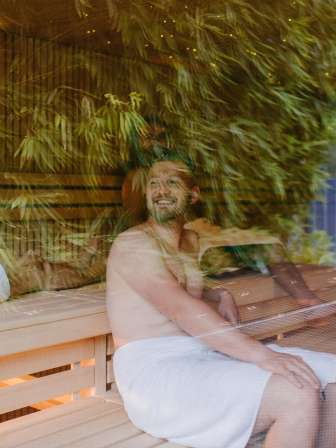 People sitting in a sauna. Bamboo leaves are reflected in the glass.
