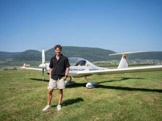 Lukas Britschgi Lukas Britschgi, European figure skating champion, stands in front of a glider in a meadow.
