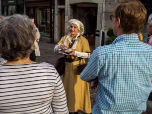 A guide dressed in a yellow robe and hood stands in front of a group.