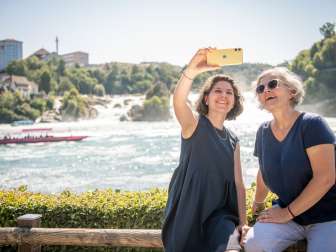 Friends at the Rhine Falls Two friends take a selfie with the Rhine Falls, the largest waterfall in Europe, in the background.